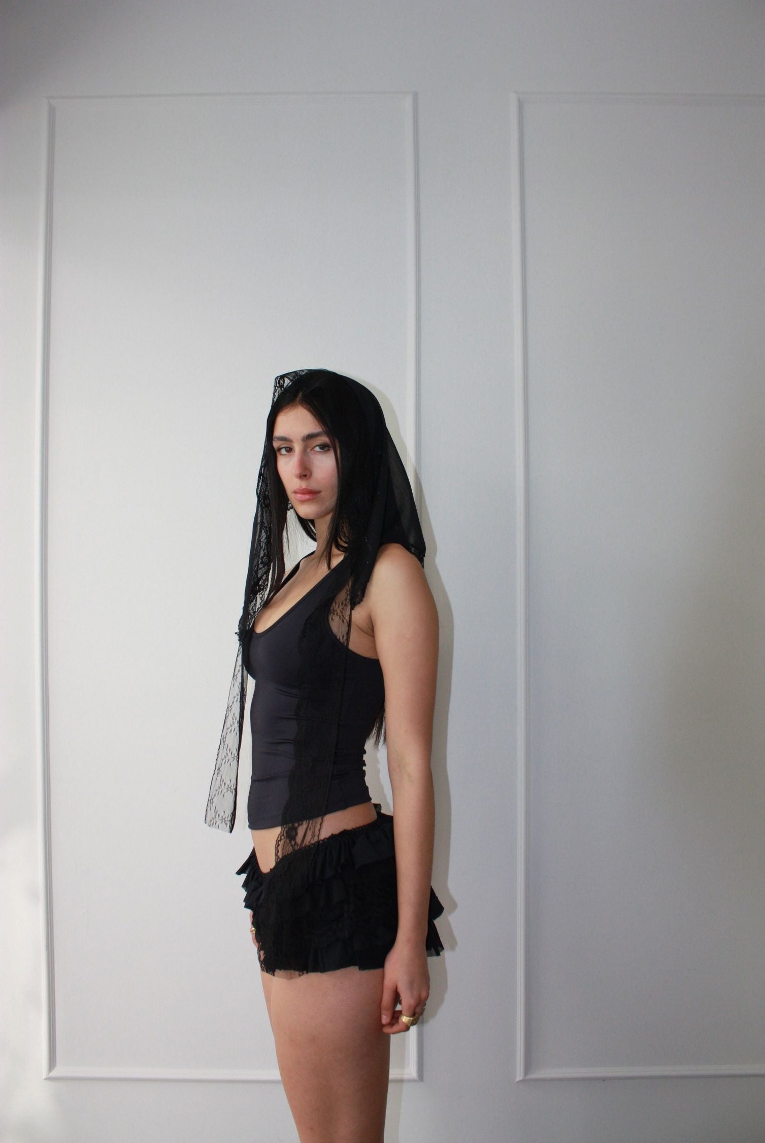 A woman embodies carefree bohemian chic as she dons a delicate black lace scarf on her head.