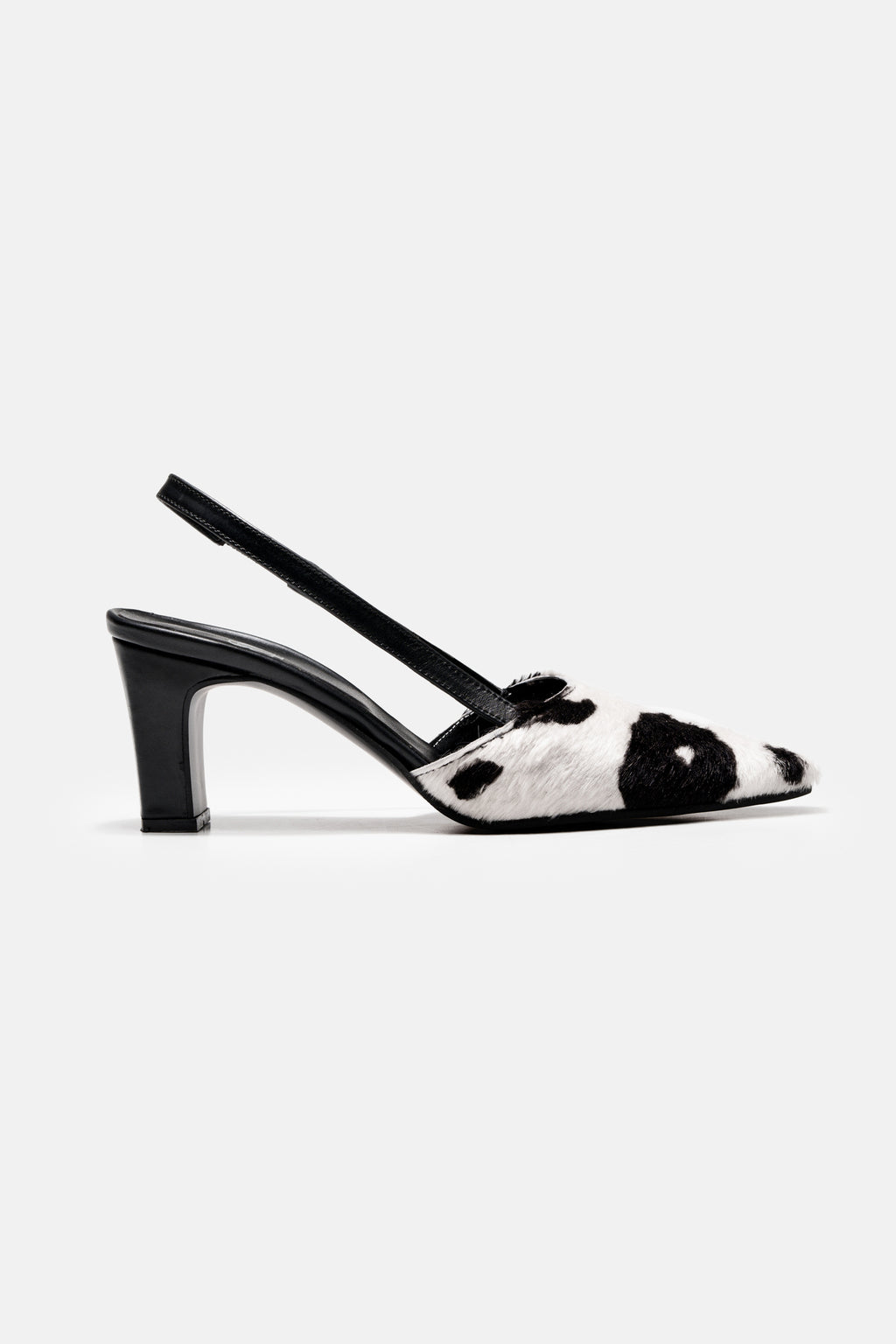 A side view of a slingback, pointed toe black heeled shoe with cow print.